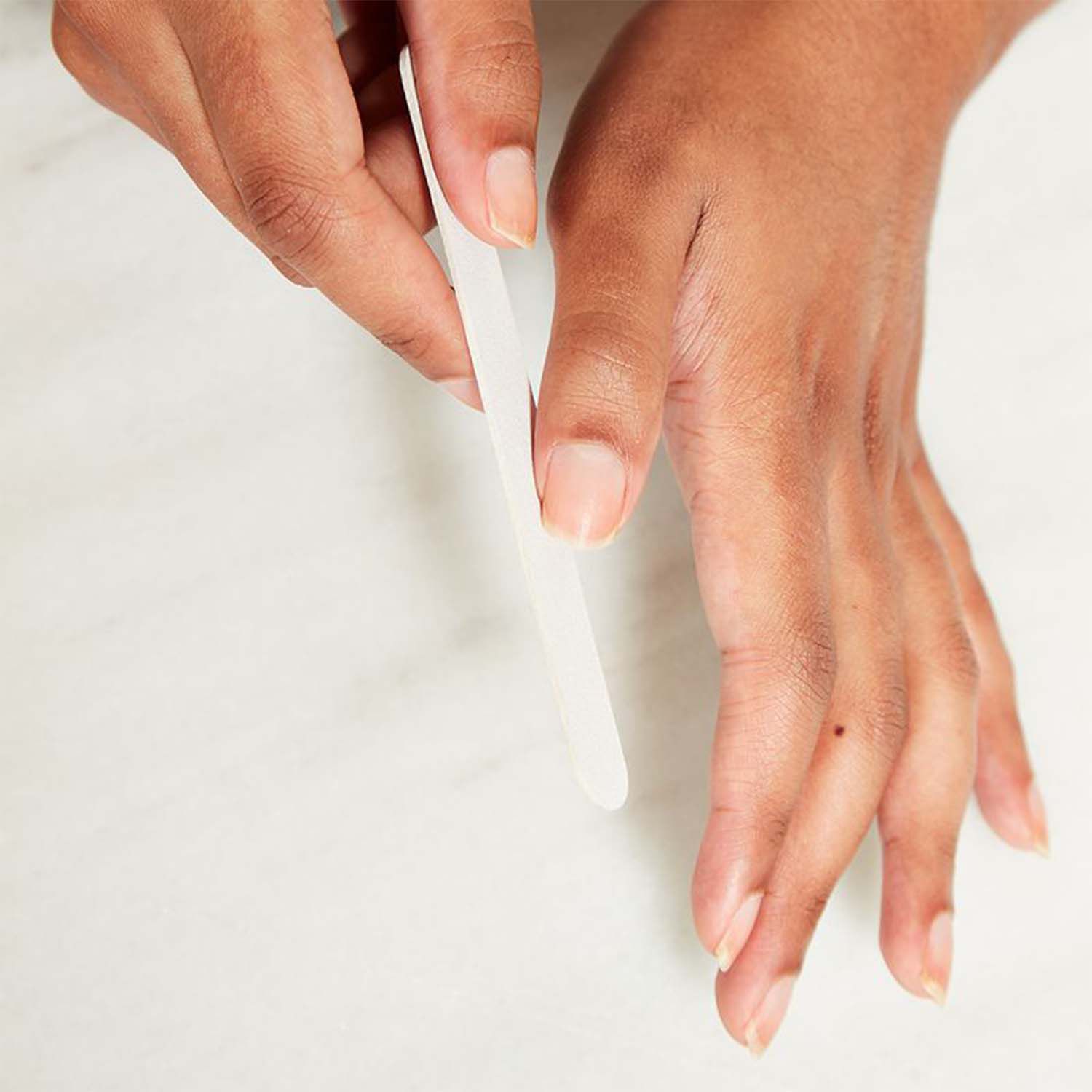 Close-up das mãos de uma mulher; ela usa uma mão para arquivar a miniatura com a outra.