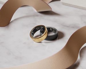 Dois anéis inteligentes, um, um ouro e um cinza, na mesa de mármore
