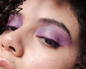 Close-up dos olhos de uma mulher com sombra roxa