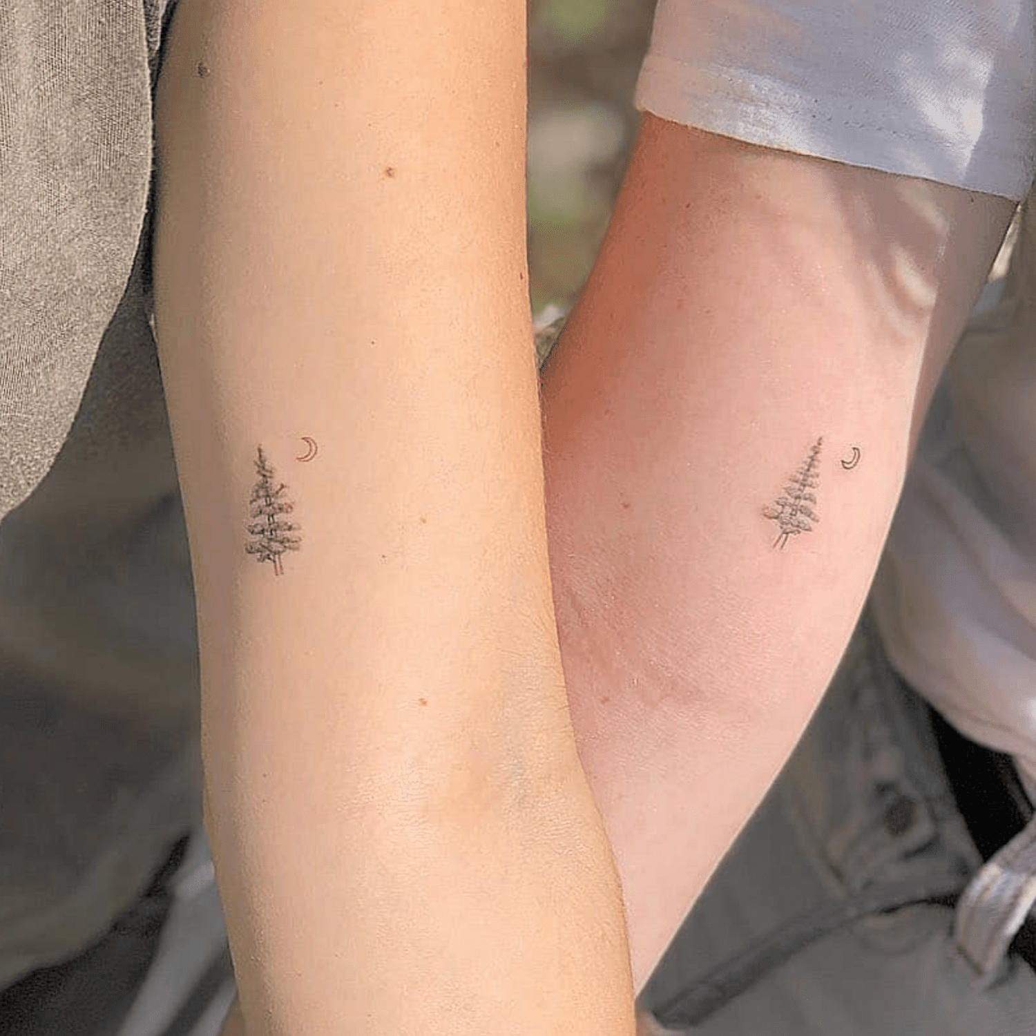 Amigos com tatuagens de pinheiro e lua crescente combinando na parte superior do braço