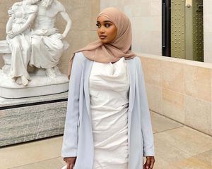 Lyuli Jaylani em um vestido branco, um banda brilhante e um hijab bronzeado em um museu em Paris.
