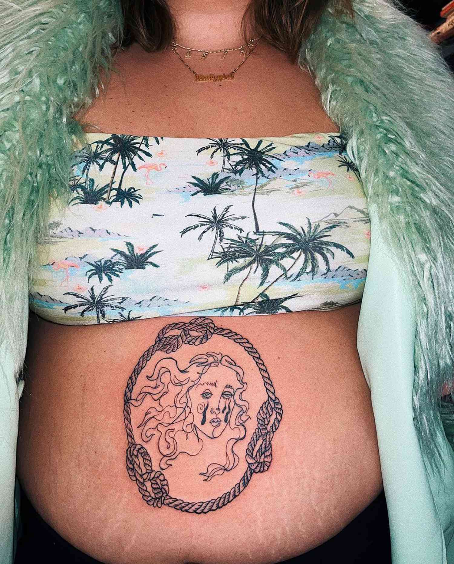 Mulher com um cardigã top e fofo com uma tatuagem de uma Vênus chorando na barriga
