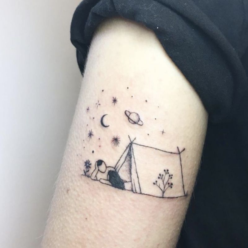 Tatuagem no braço representando duas pessoas relaxando em uma tenda sob as estrelas, a lua e Saturno