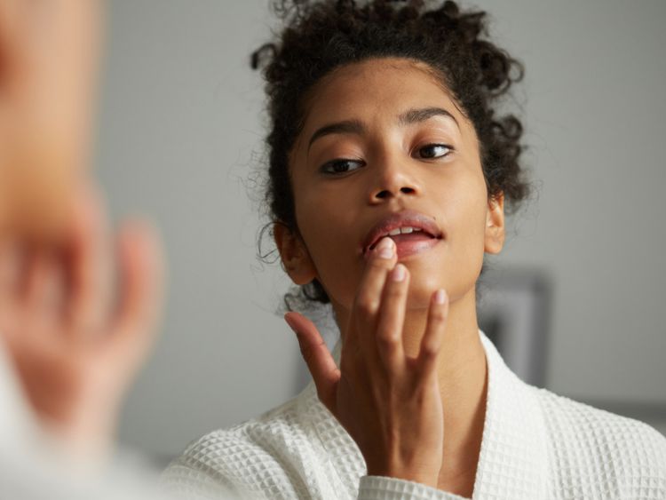 Uma mulher aplica protetor labial no espelho