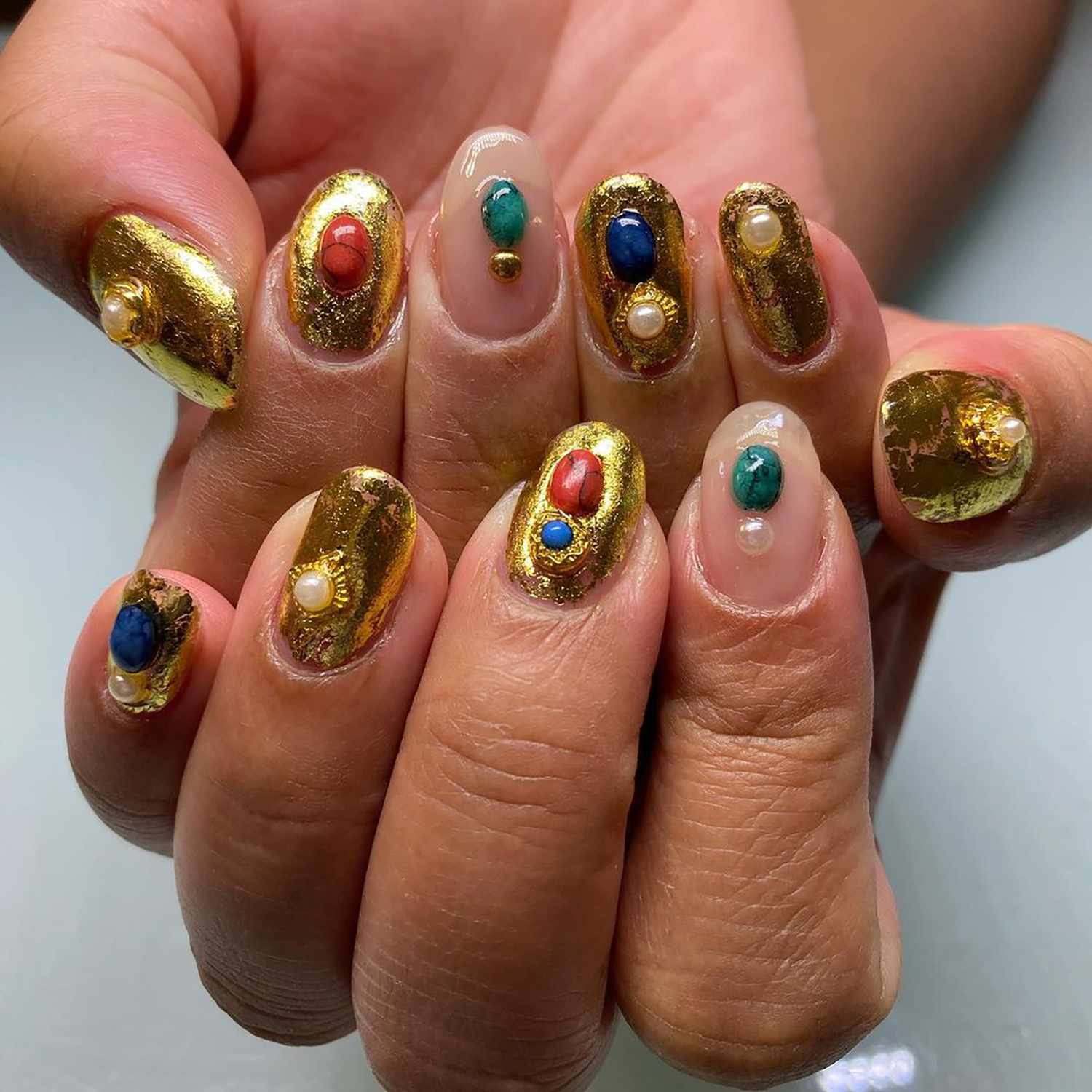 Close de manicure em ouro 24k com detalhes em pedra