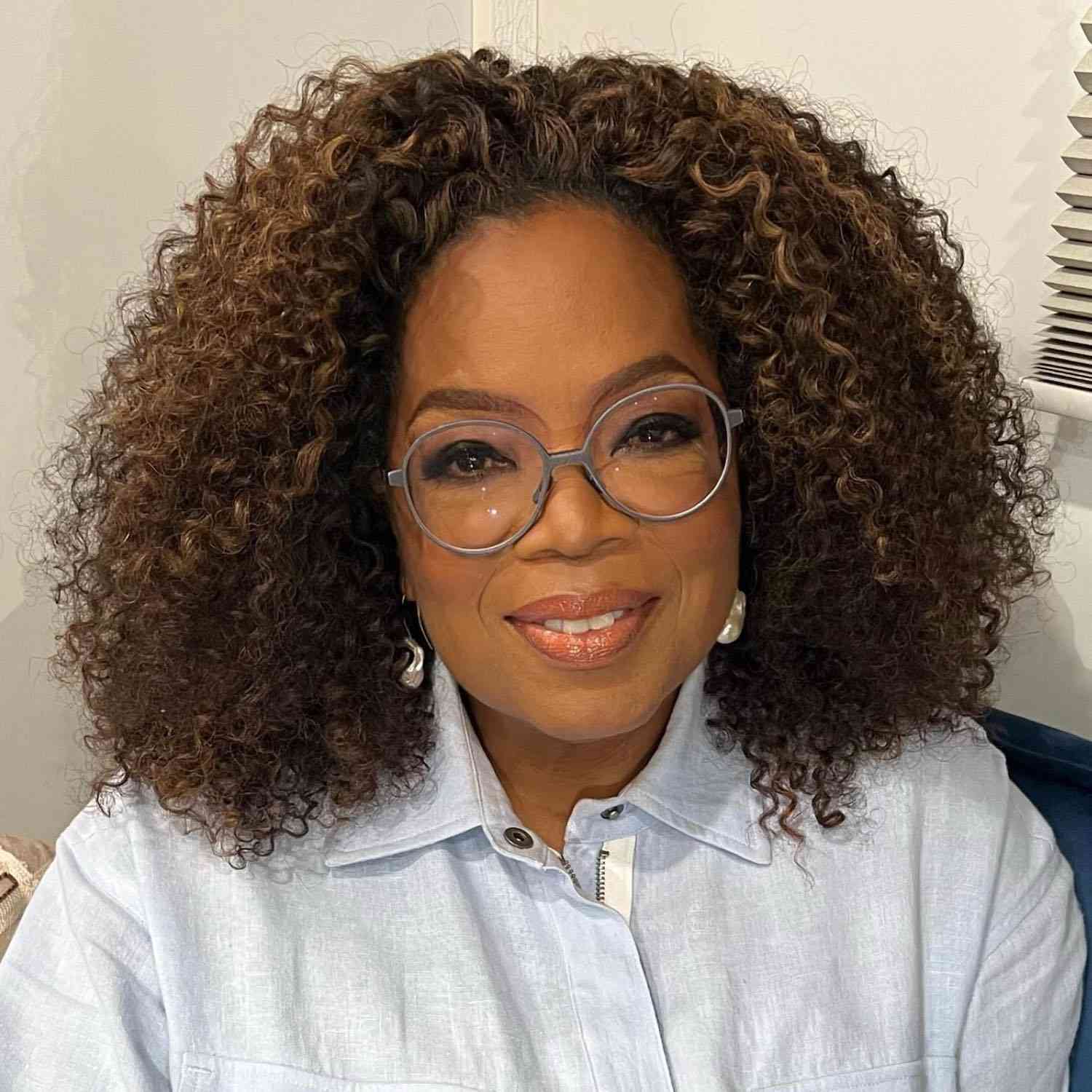 Oprah Winfrey usa um penteado naturalmente encaracolado 