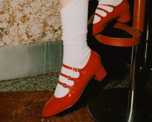 O fechamento de uma mulher puxando meias, combinada com sapatos vermelhos no salto de Mary Jane