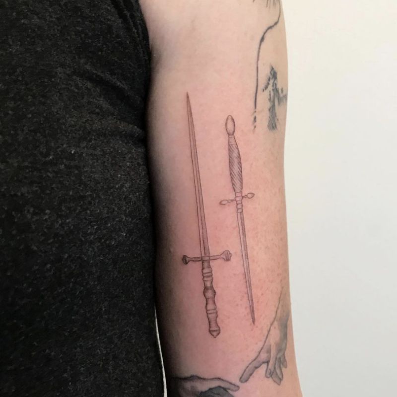 Tatuagem de espada dupla no braço