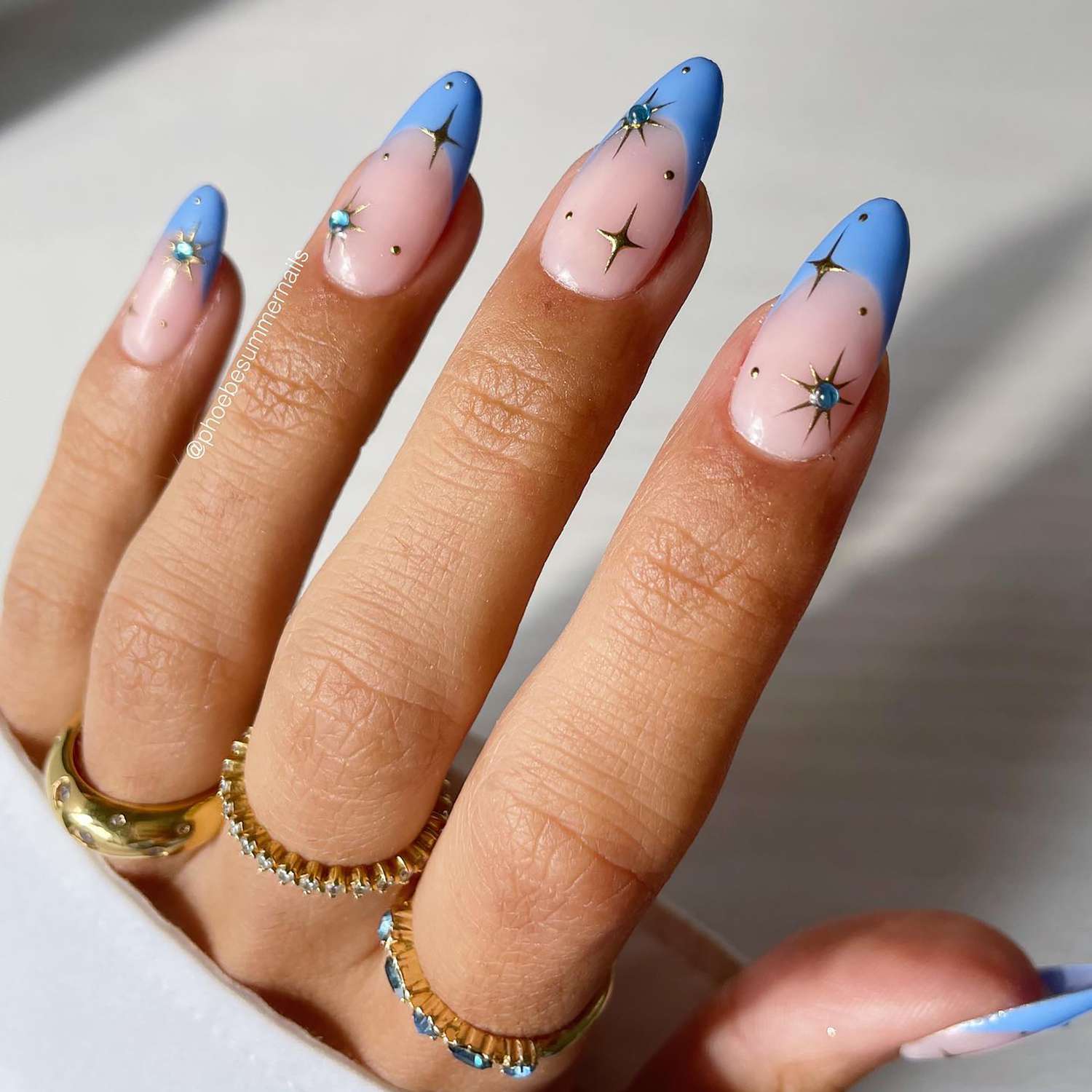 Uma manicure fechada com dicas francesas azuis e detalhes celestiais