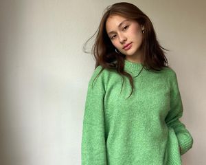 Lola Tung com suéter verde e brincos de argola prateados