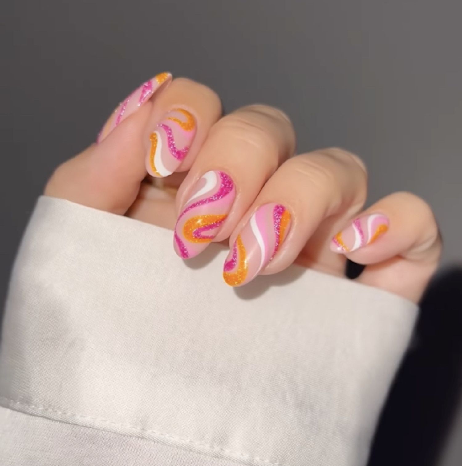 Manicure com base rosa pálido e vórtices rosa, branco e laranja