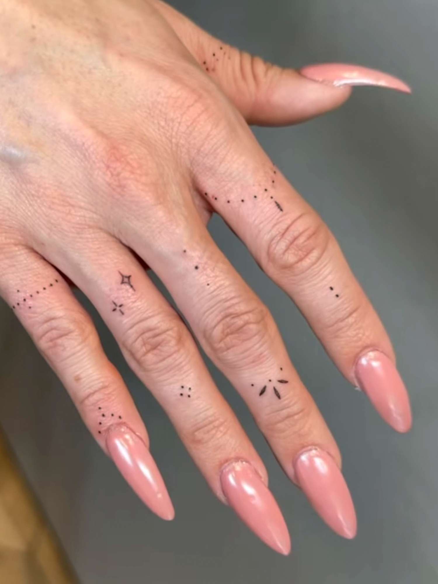 Tatuagens delicadas nos dedos das mãos com unhas longas