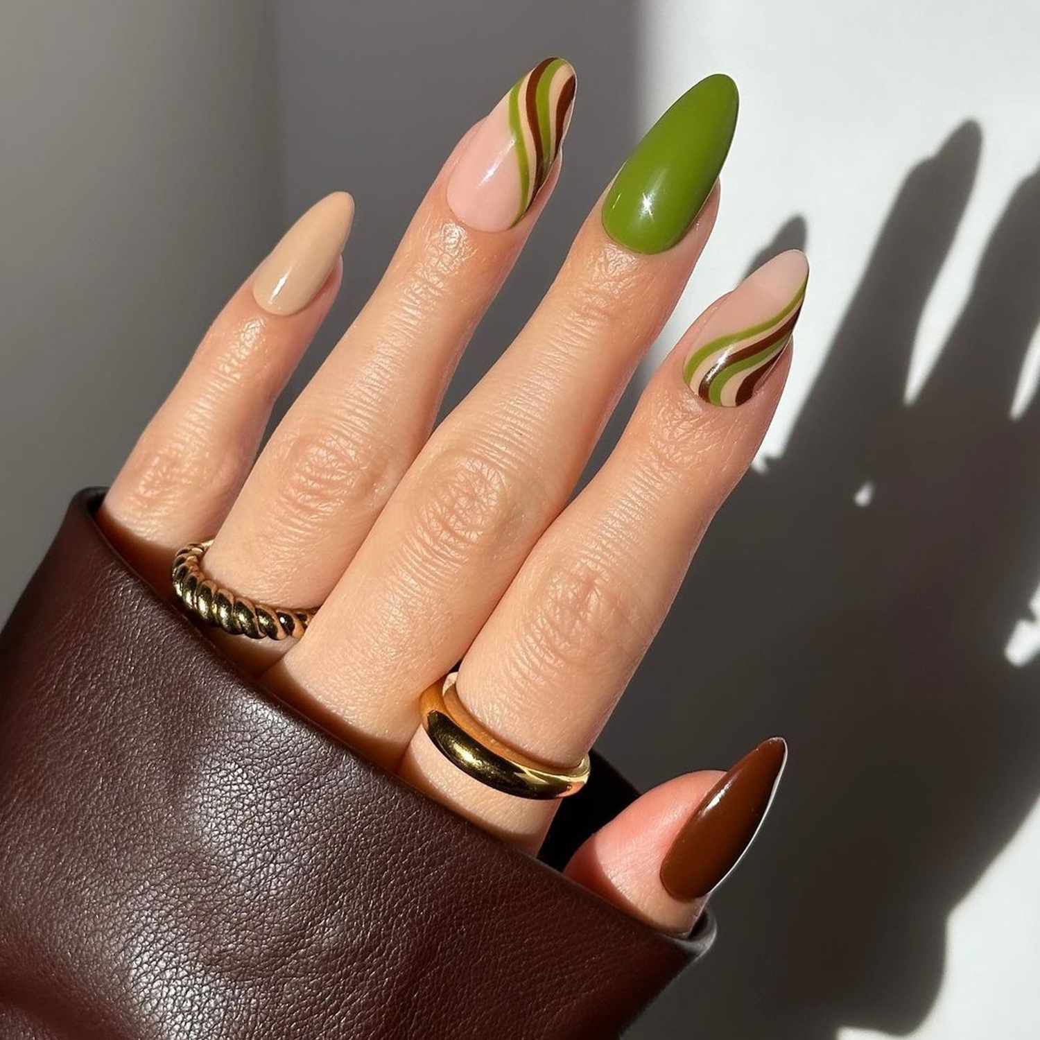 Manicure marrom e verde fosca com unhas sólidas alternadas e design espiralado