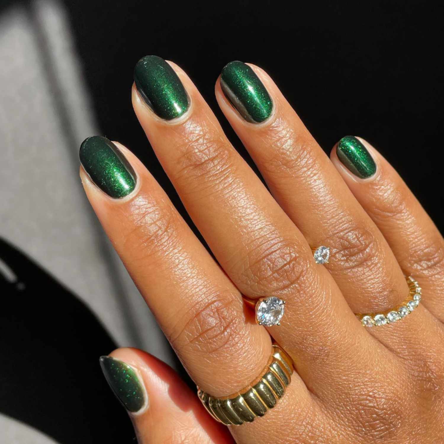 Um close de manicure verde esmeralda com rings de pisca e diamante quase imperceptíveis