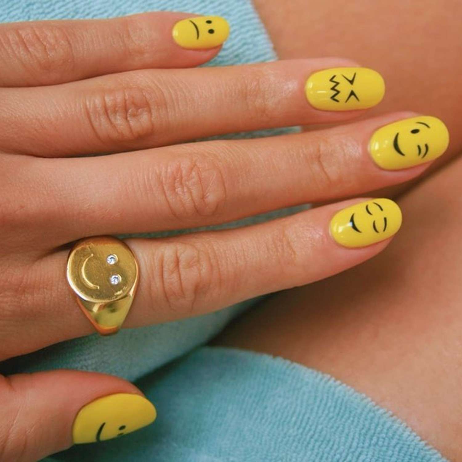 Unhas com emoji em uma base amarela e vários padrões em rostos