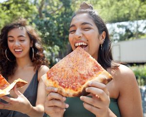 Meninas comem pizza no parque