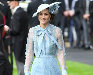 Kate Middleton em um vestido azul claro com mangas transparentes e um chapéu com detalhes florais