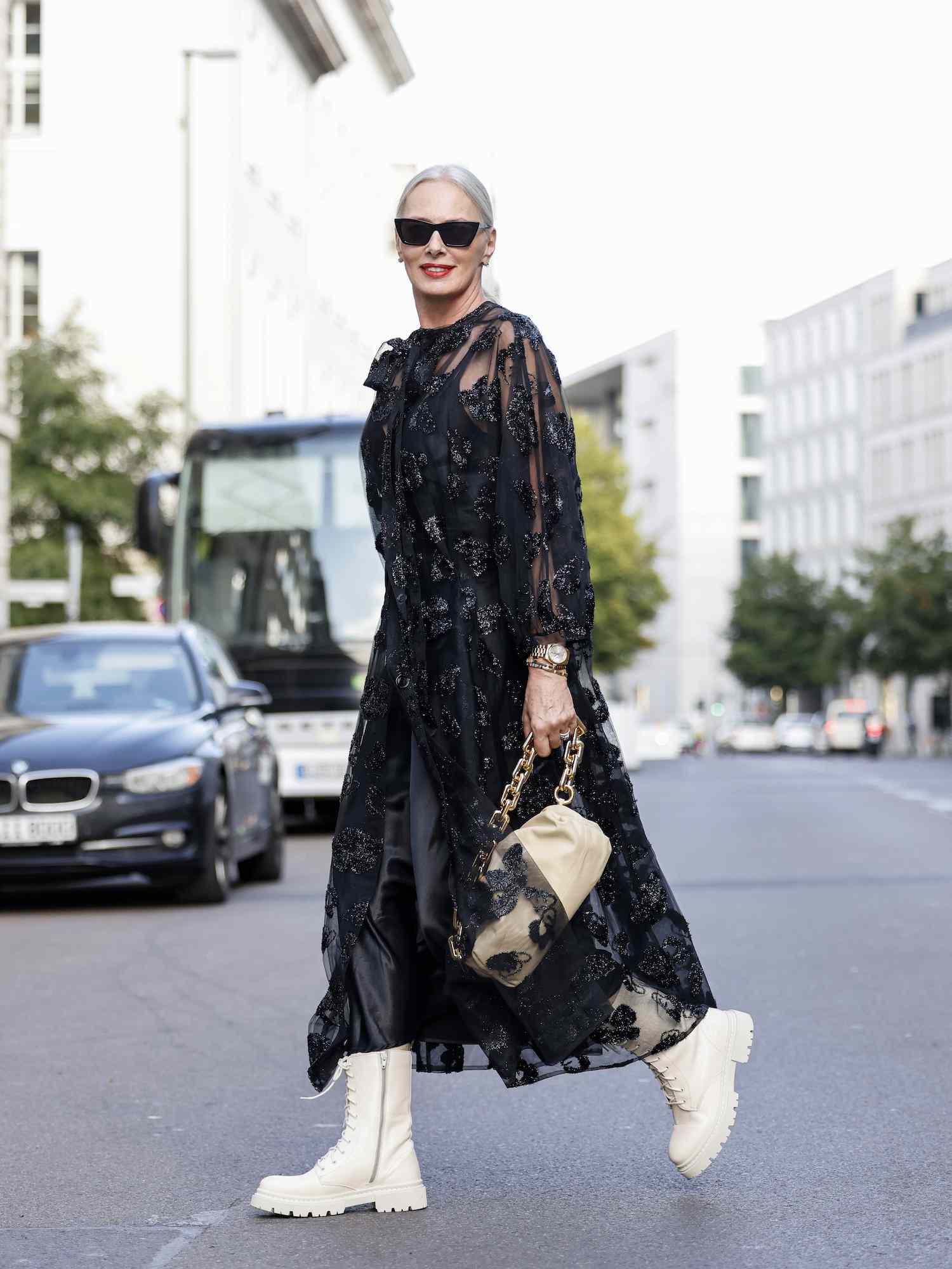 Petra van Bremen usa um vestido maxi floral, botas brancas de amarrar, óculos escuros e uma bolsa bege