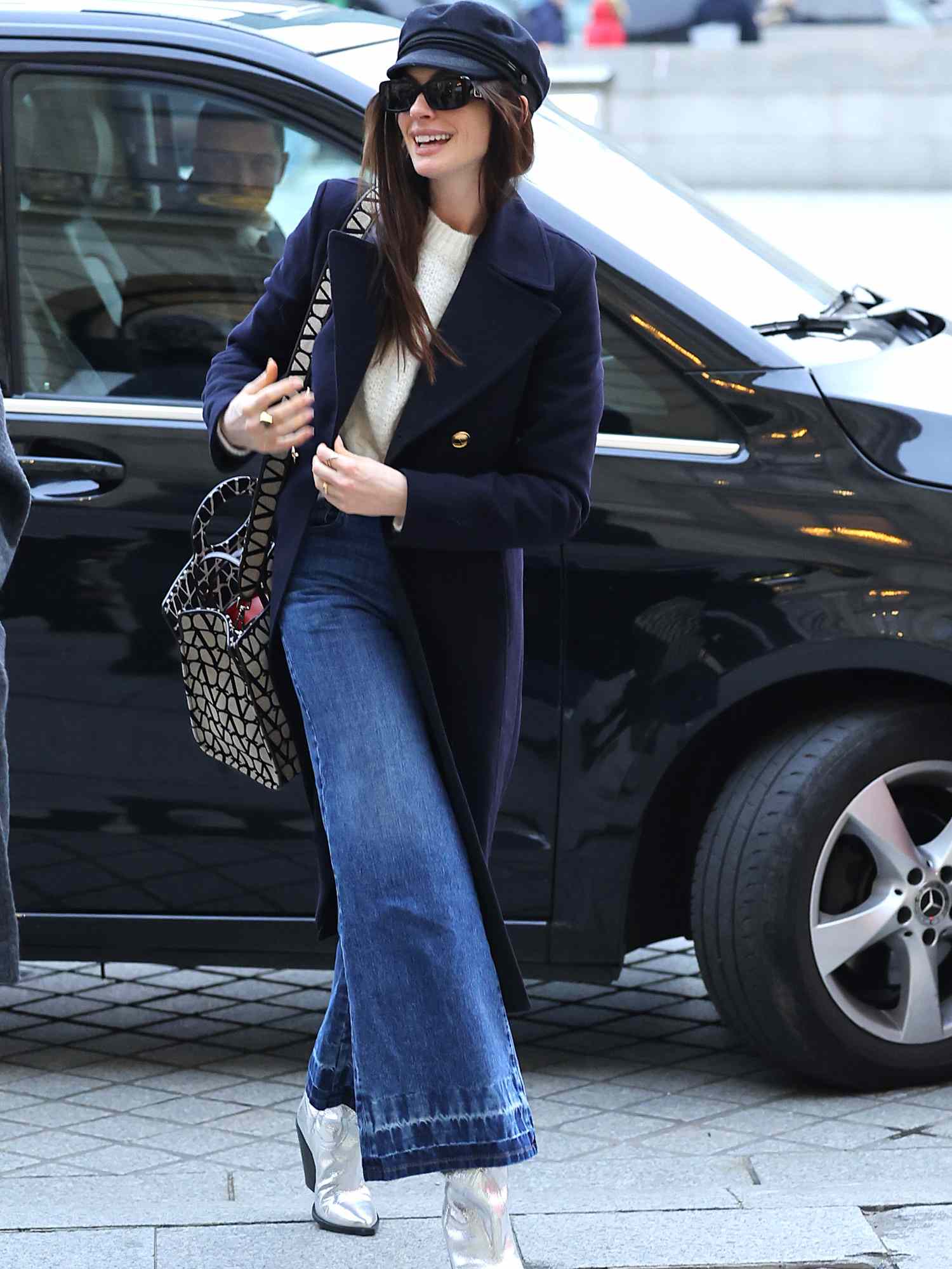 Anne Hathaway em jeans, casaco de lã escura e botas prateadas