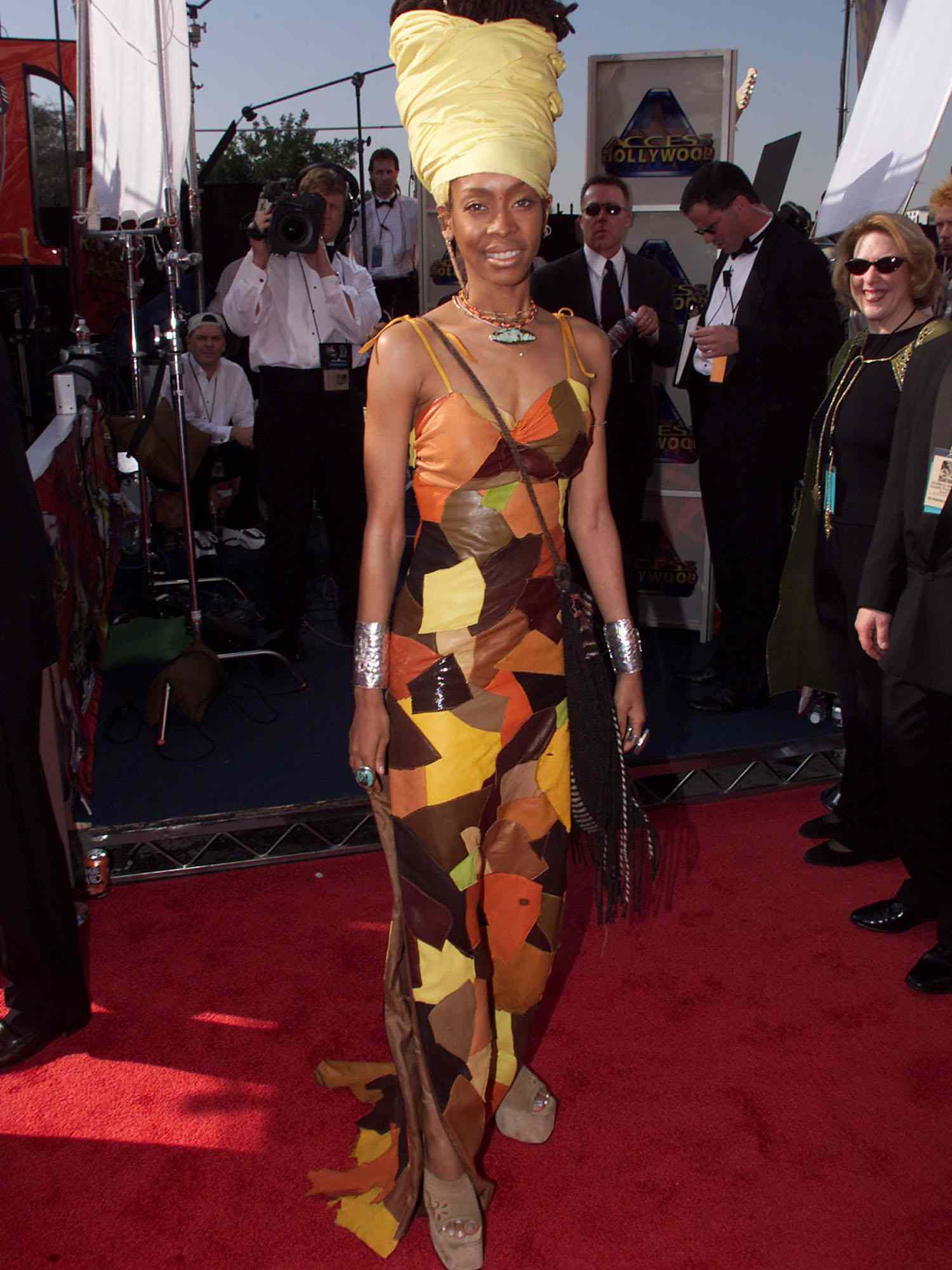 Erica Badu em um vestido de couro no estilo de retalhos e o cocar amarelo de Nefertiti no Grammy de 1999