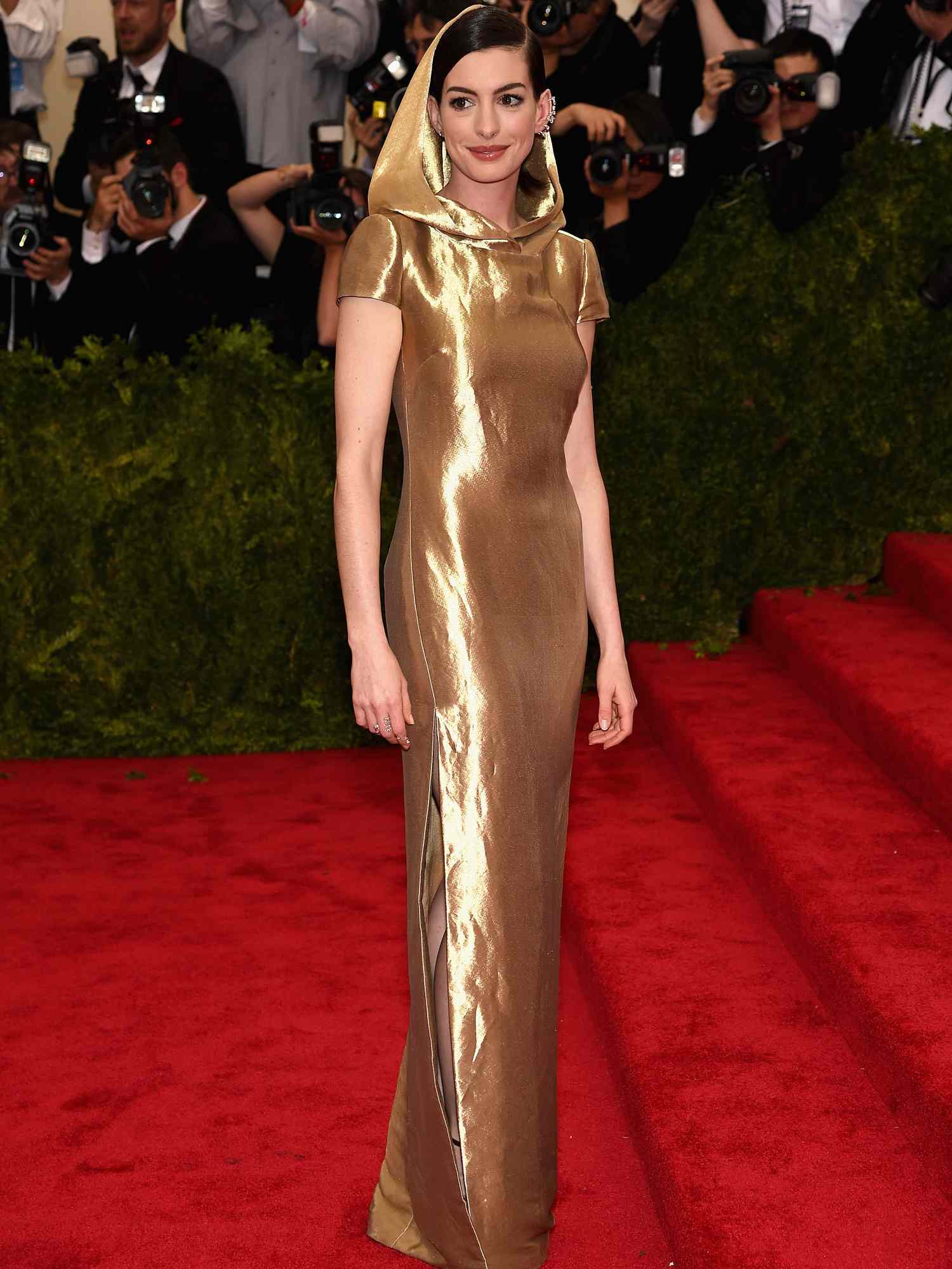 Anne Hathaway com vestido dourado Ralph Lauren com capuz no Met Gala 2024