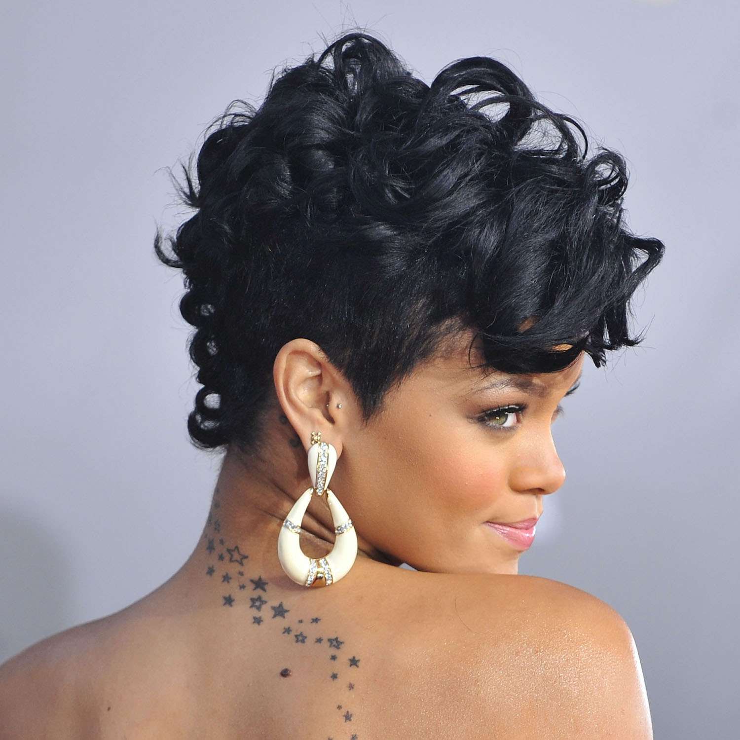 Rihanna com um corte de cabelo curto e tatuagem encaracolado na forma de uma estrela nas costas