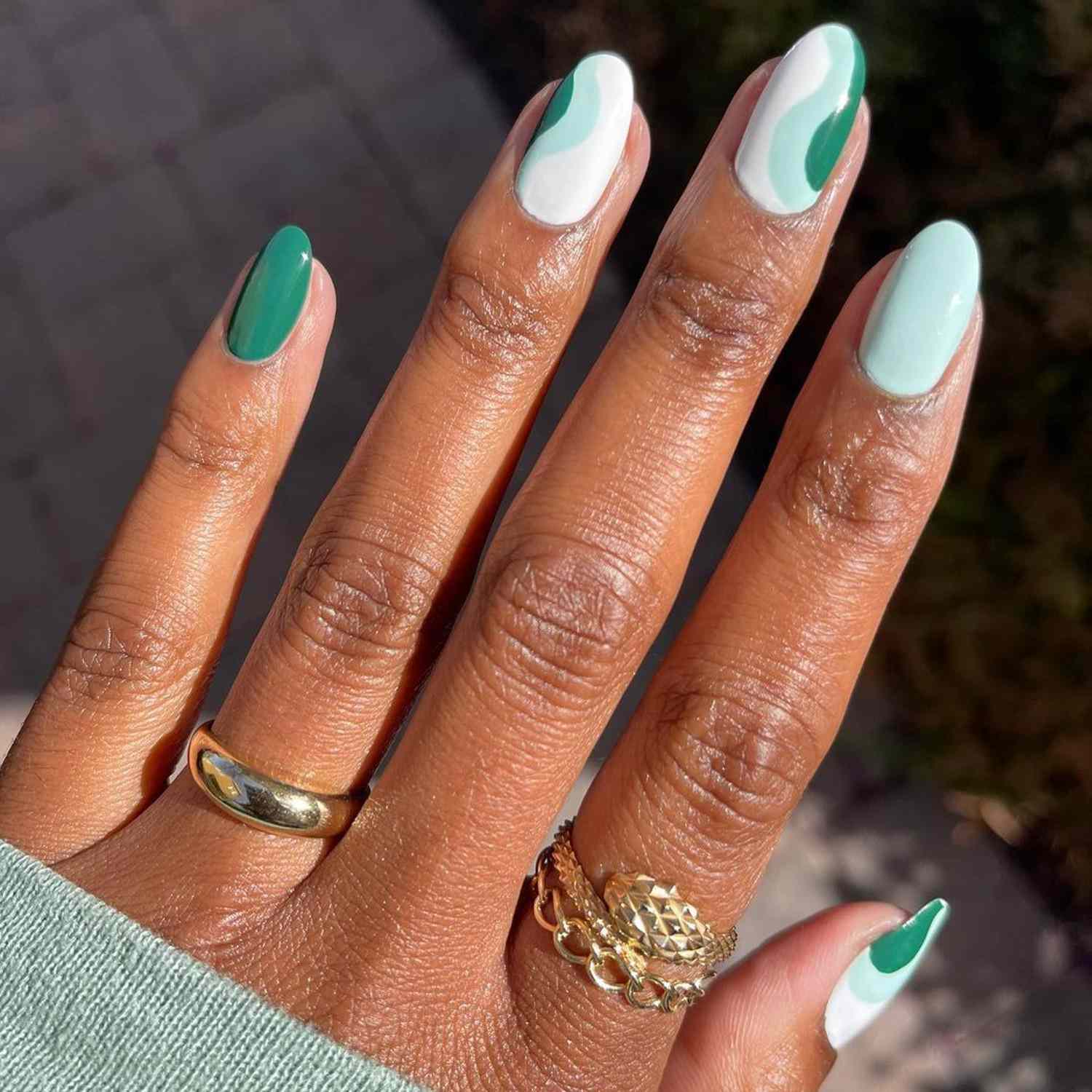 Manicure verde-escuro, azul e branco com um design de onda nas unhas