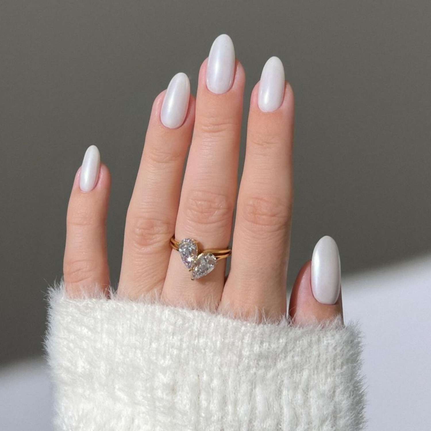 Fecha r-Up Manicure branca perolada no braço com um anel na forma de um coração de diamante