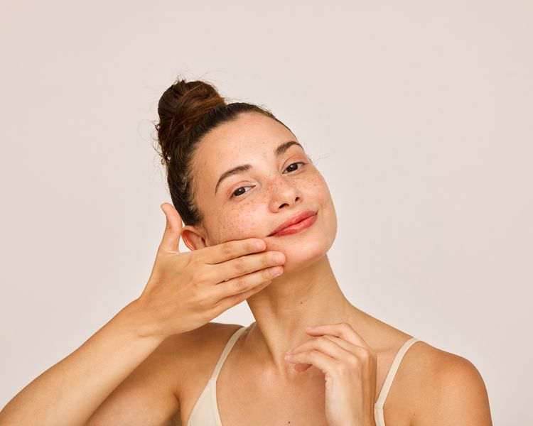 Uma mulher aplica um produto de cuidados com a pele em suas bochechas