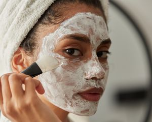 Uma mulher aplica uma máscara facial com um pincel
