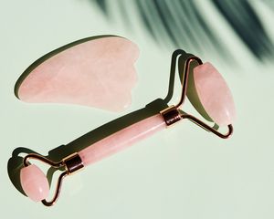 Instrumentos gua-sha do quartzo rosa em um fundo verde