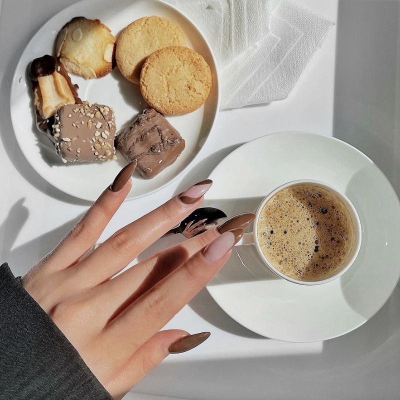 Manicure francesa da cor de Mokko no cenário de biscoitos e café