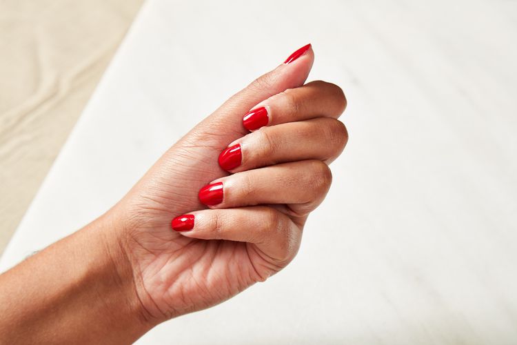 Mão feminina com manicure vermelha brilhante