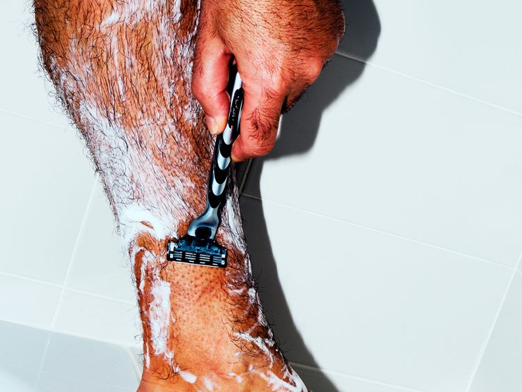 Um homem raspa a perna no chuveiro.