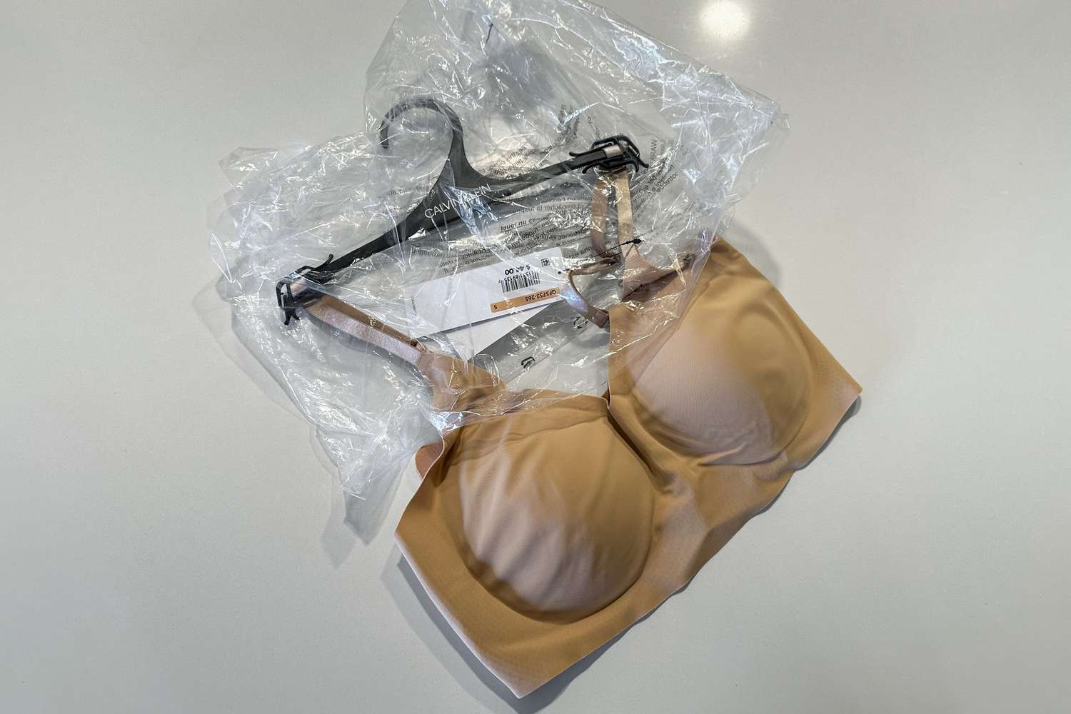 Um bralette invisível da Calvin Klein está sobre o balcão e é retirado da embalagem plástica.