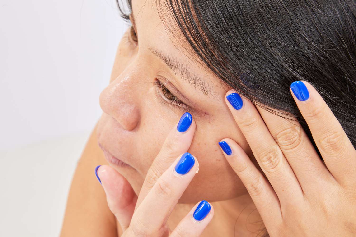 Uma pessoa aplica o creme para os olhos peptídicos de vitamina C + de verão na área dos dedos