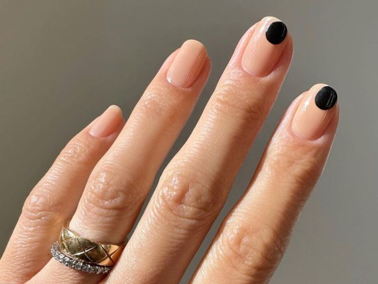 Manicure nude com duas unhas acentuadas com pontos pretos