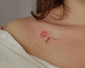 Close de tatuagem de peônia vermelha/rosa e verde na clavícula