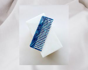 Lindo pente azul com dentes largos sobre um fundo branco.
