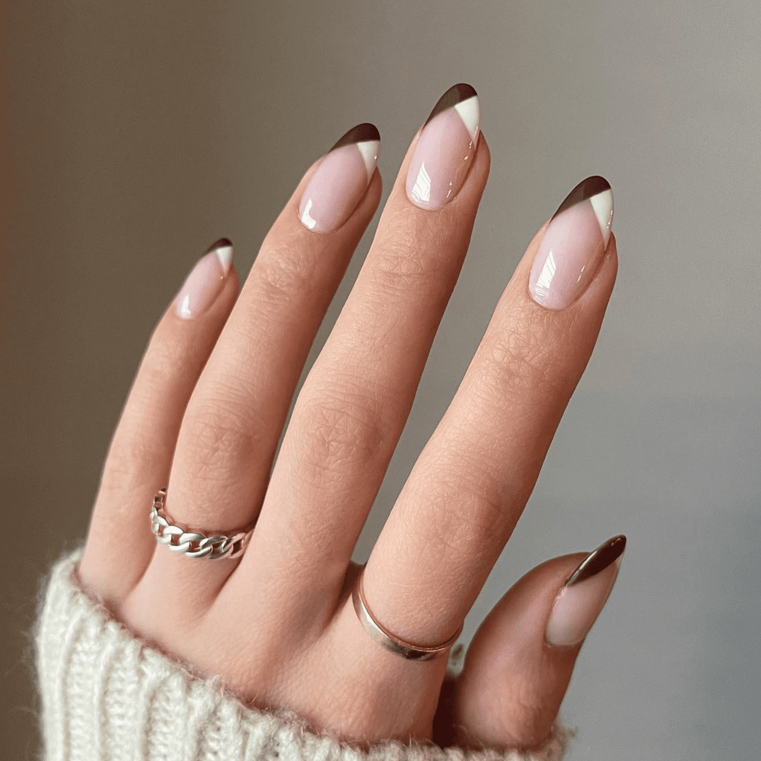 Unhas redondas de comprimento médio com manicure francesa marrom e branca.