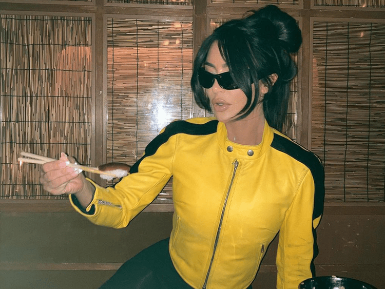 Kim Kardashian em uma jaqueta amarela e com um estrondo torto