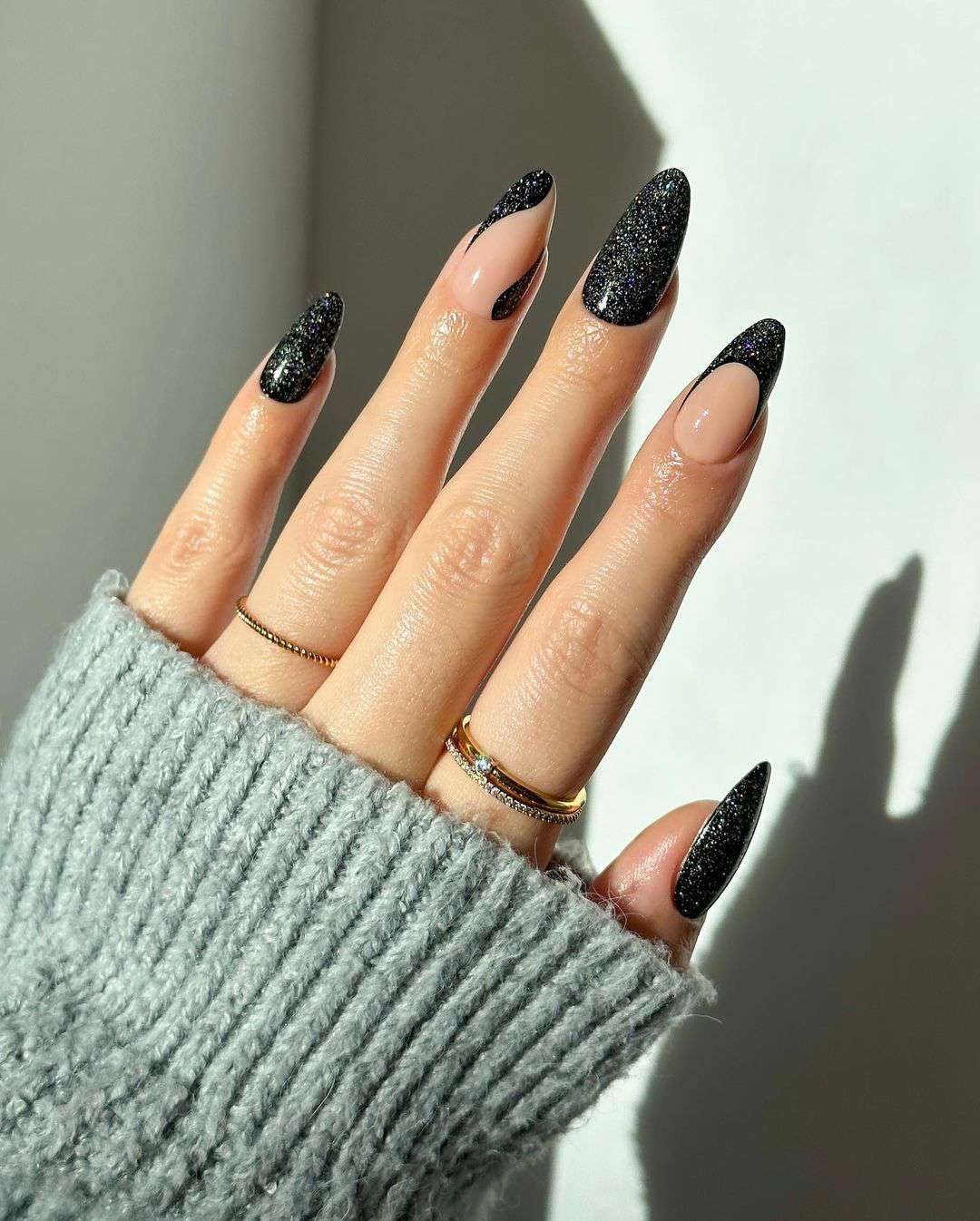 Close-up de uma mão com manicure francesa incompatível com glitter preto
