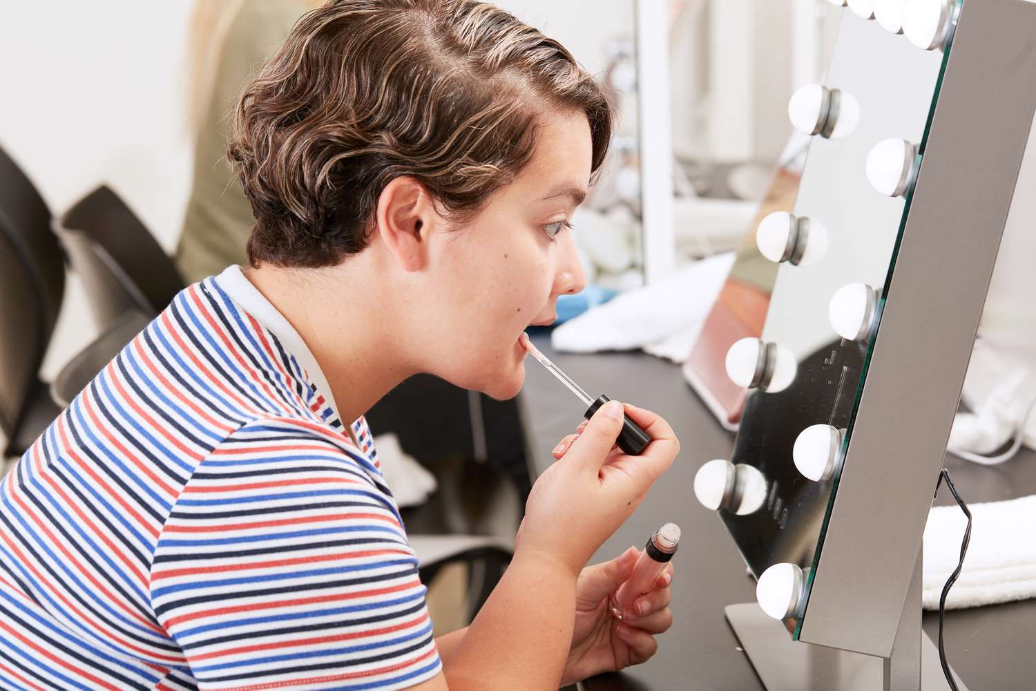 Homem aplicando brilho labial e. l. f. Cosméticos Lip Plumping Gloss nos lábios no espelho