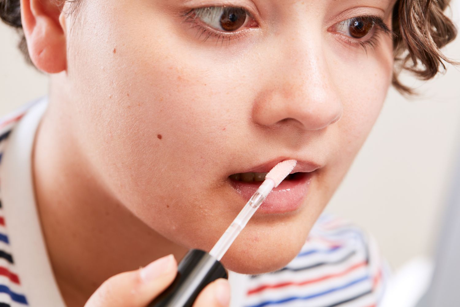 Homem aplicando brilho labial e. l. f. Cosmetics Lip Plumping Gloss nos lábios usando um aplicador