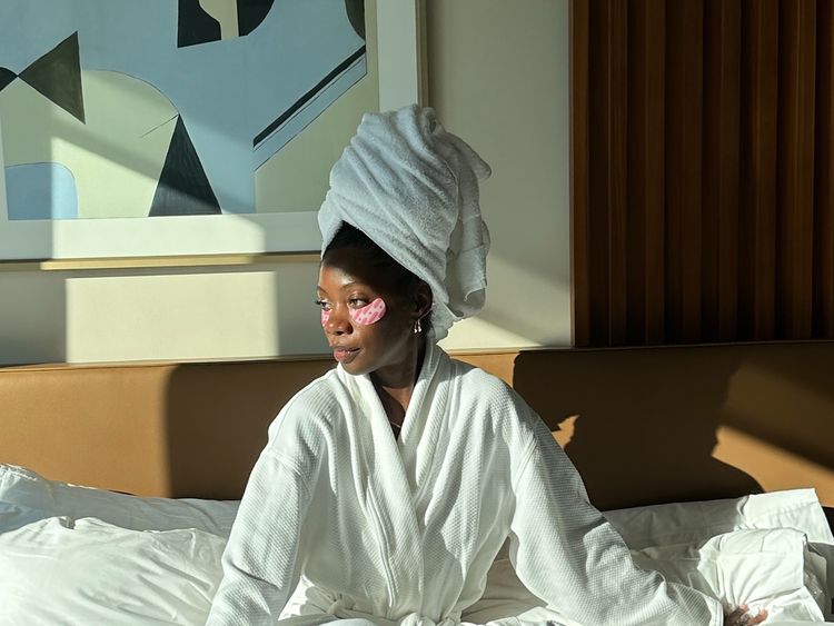 O fechamento do editor social Byrdie Jasmine Phillips no roupão de banho, seu cabelo está embrulhado em uma toalha