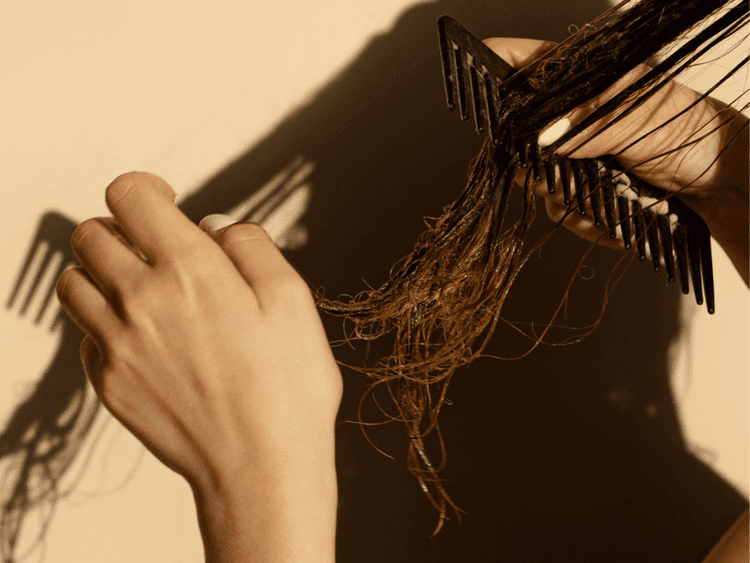 Um plano próximo de uma mão penteando cabelos compridos.