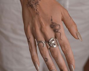 Close de uma mão com muitas pequenas tatuagens