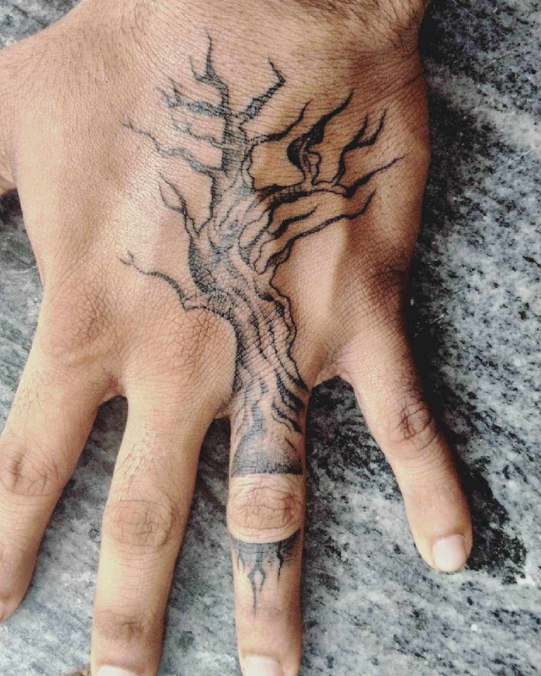 Close de uma mão com uma tatuagem de árvore