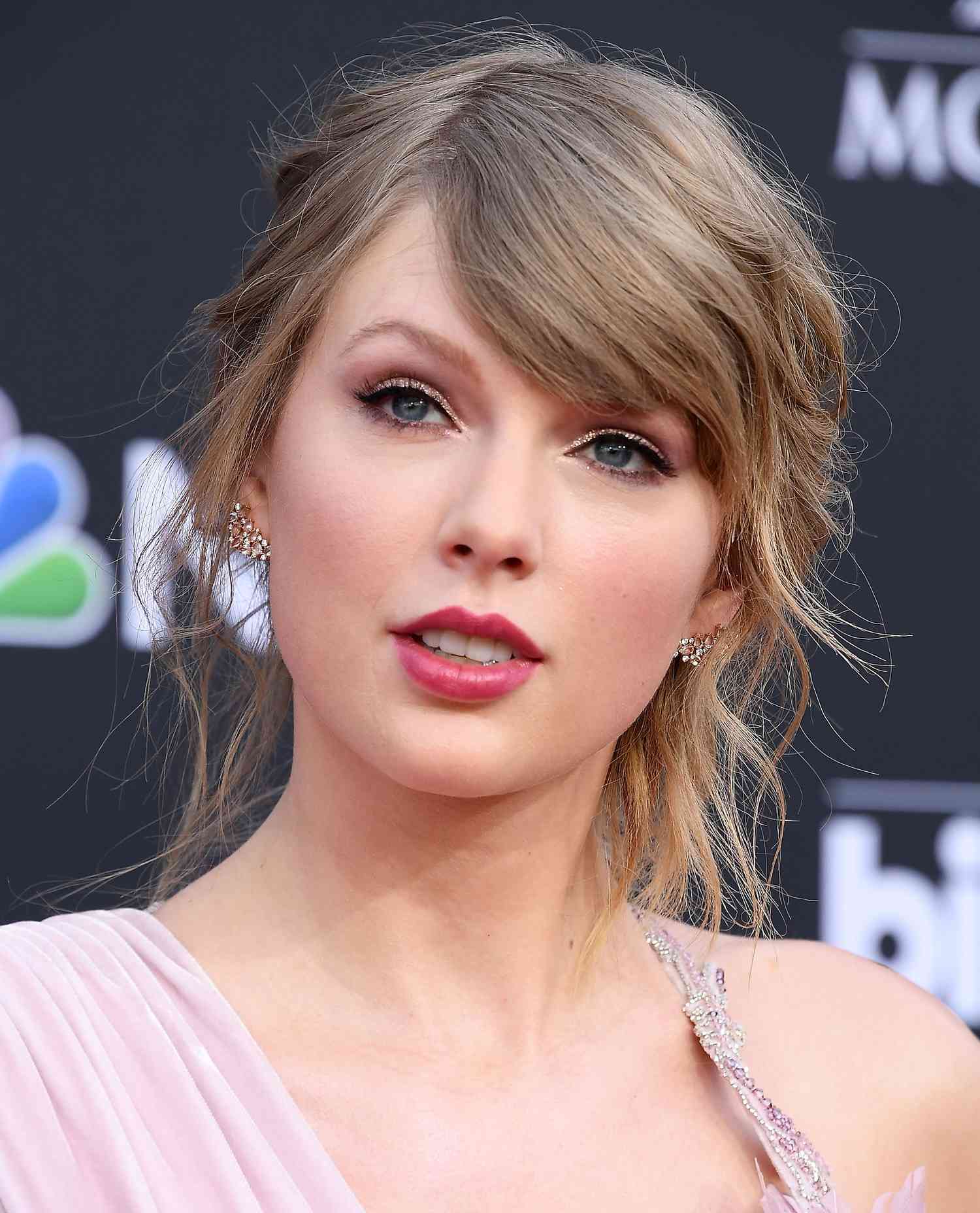 Taylor Swift usa orelhas de ouro rosa brilhante e batom rosa