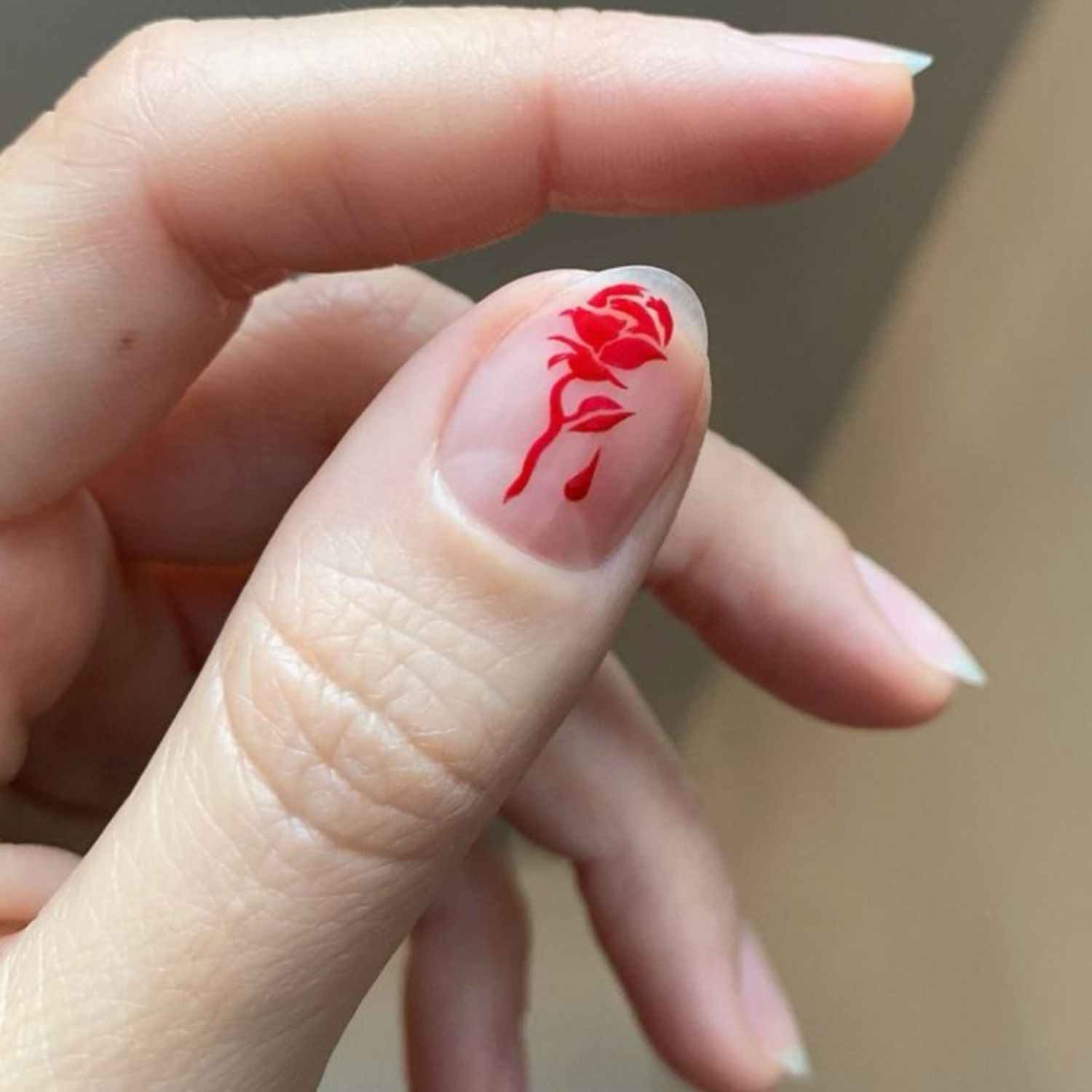 Um polegar nu com uma rosa vermelha desenhada em um estêncil.